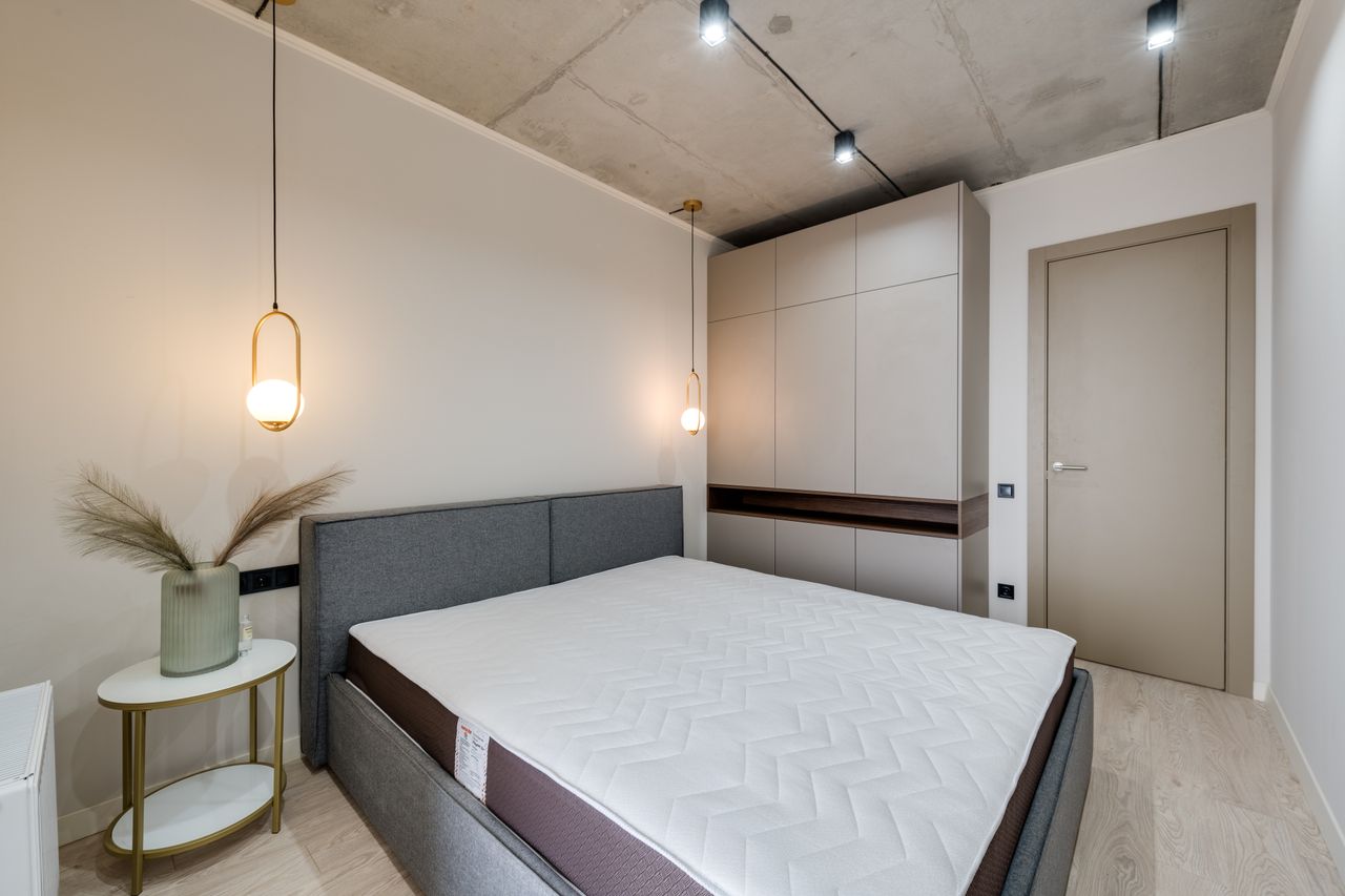 A minimalist bedroom featuring a gray bed, warm lighting, and sleek storage solutions.